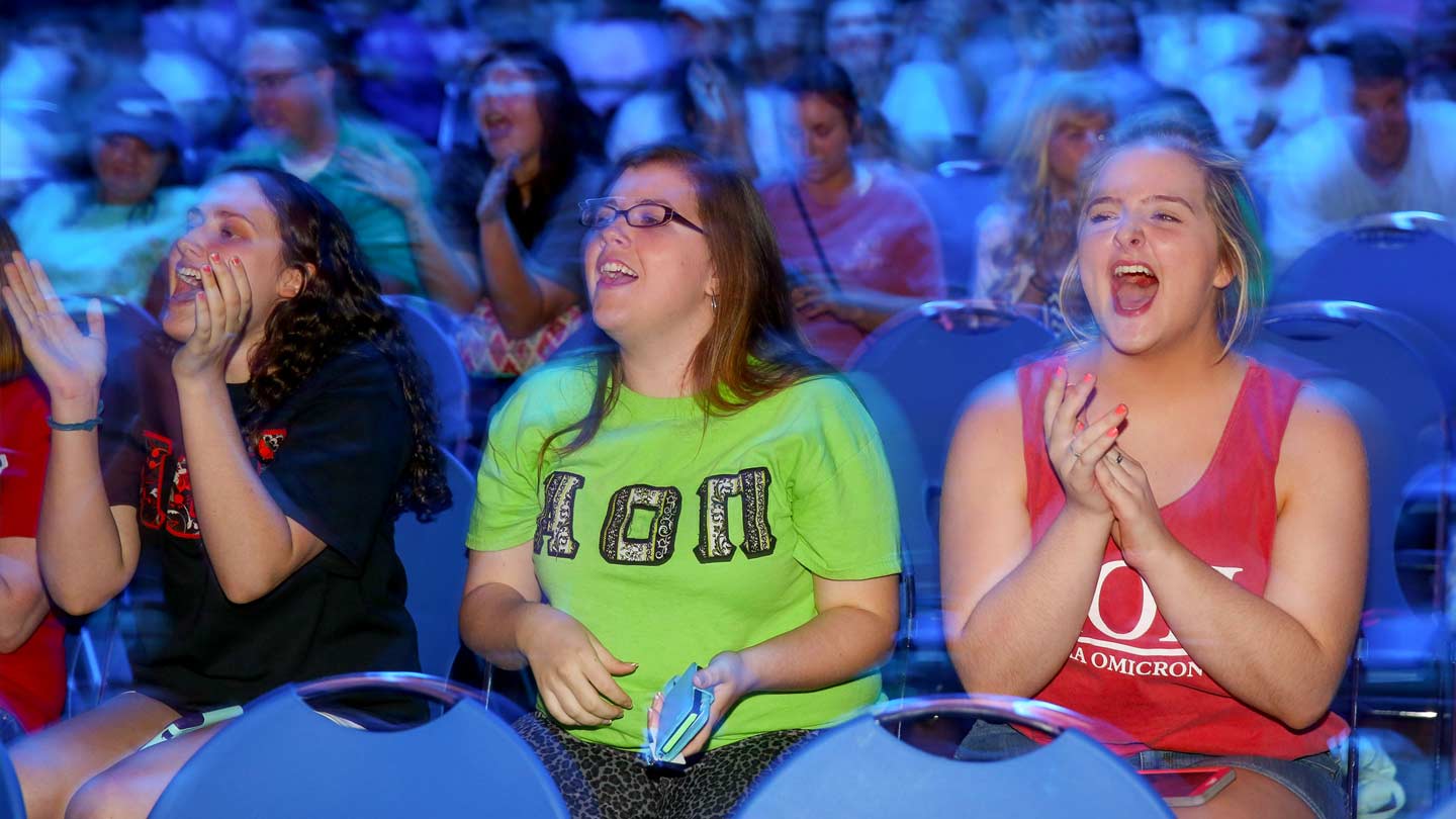 Photo of three women clapping and screaming in audience